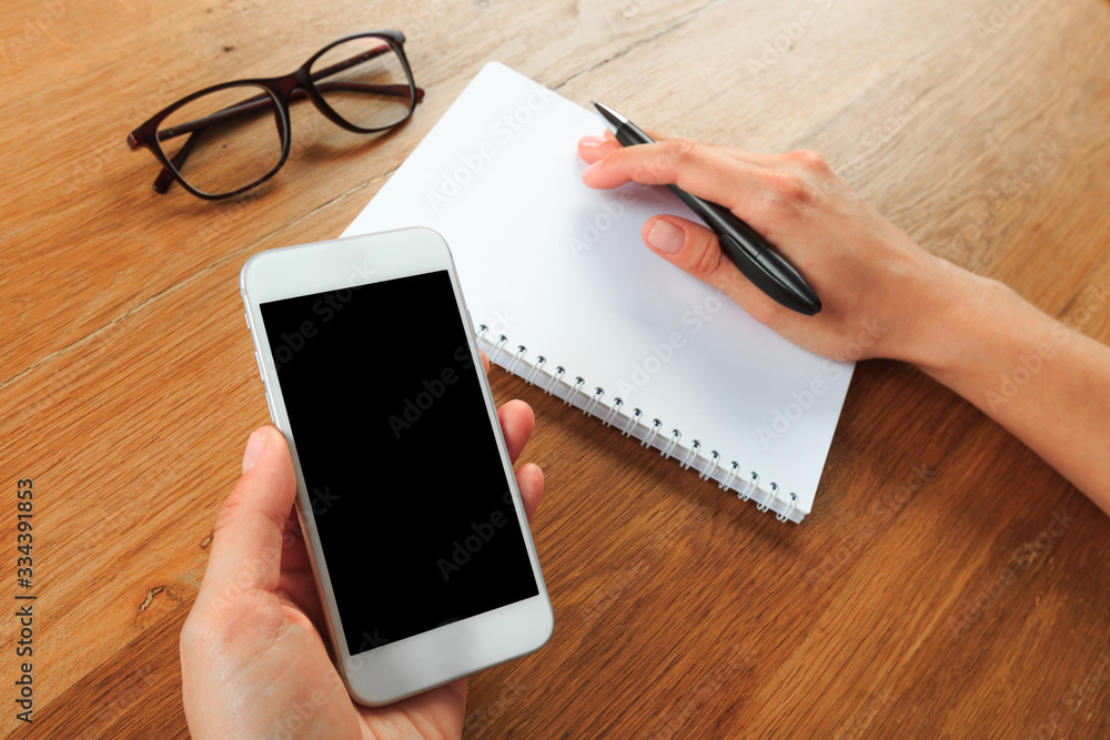 female hands holding smart phone on wooden background , place for your text female hands holding smart phone on wooden background , place for your text