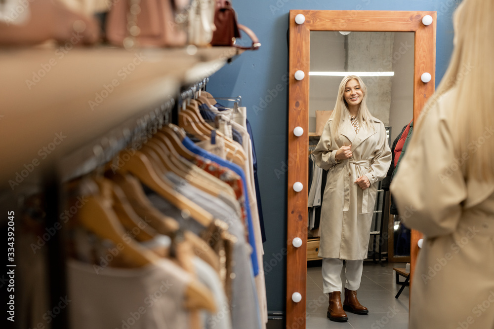 Pretty young stylish female standing in front of mirror in boutique Pretty young stylish female standing in front of mirror in boutique