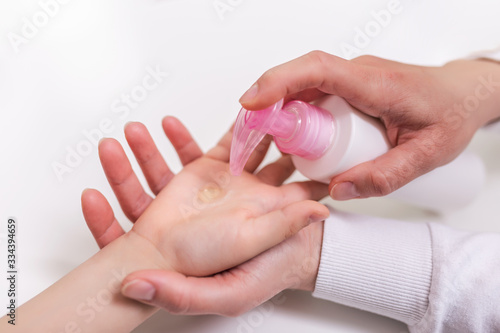 Mother applying cleaning gel on kids hand  applying alcohol gel to make cleaning and clear germ  bacteria  Health care concept  coronavirus pandemic. COVID-19. stay at home