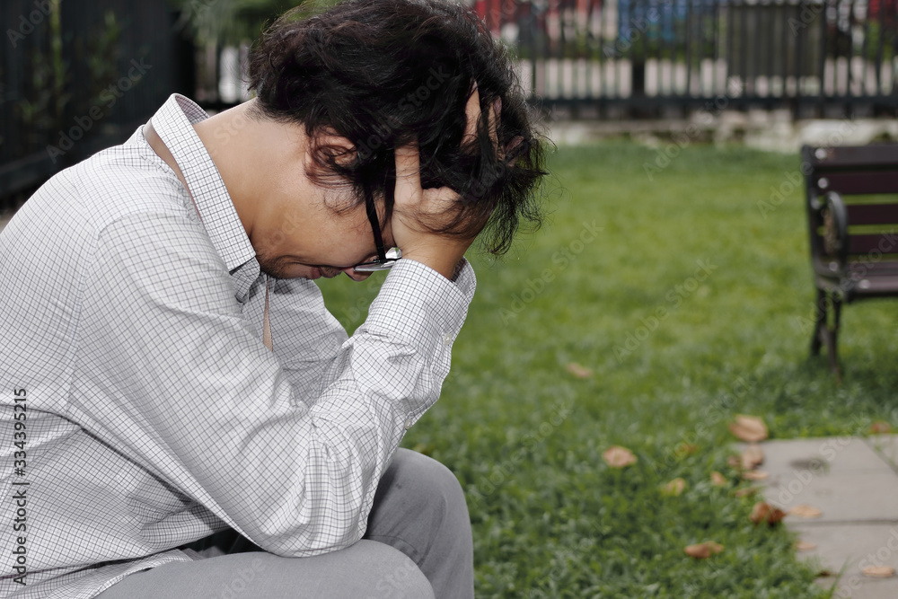 Depressed stressed young Asian business man with hands on head. Unemployment and layoff concept. Depressed stressed young Asian business man with hands on head. Unemployment and layoff concept.