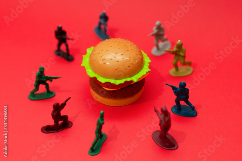 Hamburger surrounded by toy soldiers  burger wars concept or war on fast food concept.