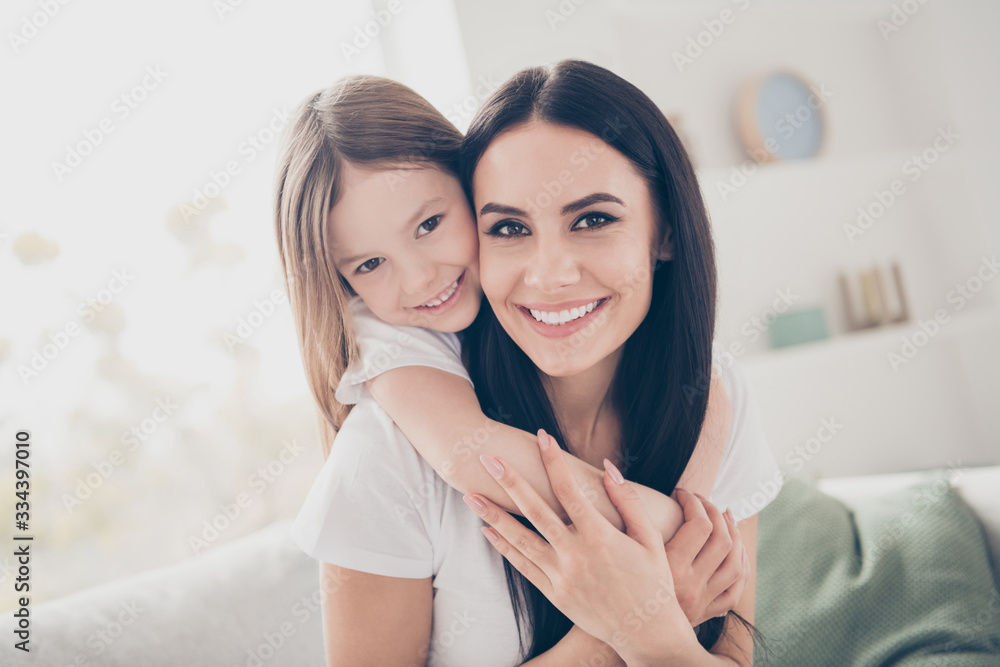 Closeup photo of cute small girl young charming mommy hugging holding each other close piggyback sitting comfy sofa spend free time together home house indoors Closeup photo of cute small girl young charming mommy hugging holding each other close piggyback sitting comfy sofa spend free time together home house indoors