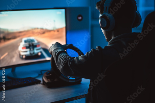 The guy gamer with headphones playing video games in the dark room photo