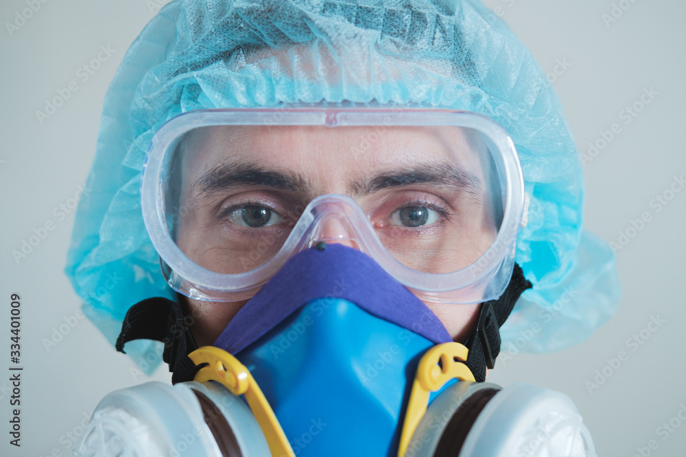 Man in protective face mask, eyeglasses and head protection, focus on eyes. Medical personell, scientist or MD in work gear, concept of covid-19, virus, epidemic and vaccine development Man in protective face mask, eyeglasses and head protection, focus on eyes. Medical personell, scientist or MD in work gear, concept of covid-19, virus, epidemic and vaccine development