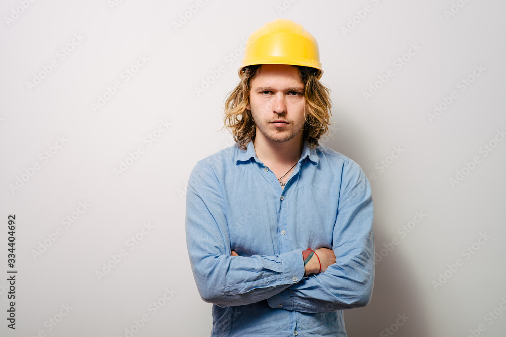 Handsome young man with protective helmet on his head and arms crossed Handsome young man with protective helmet on his head and arms crossed