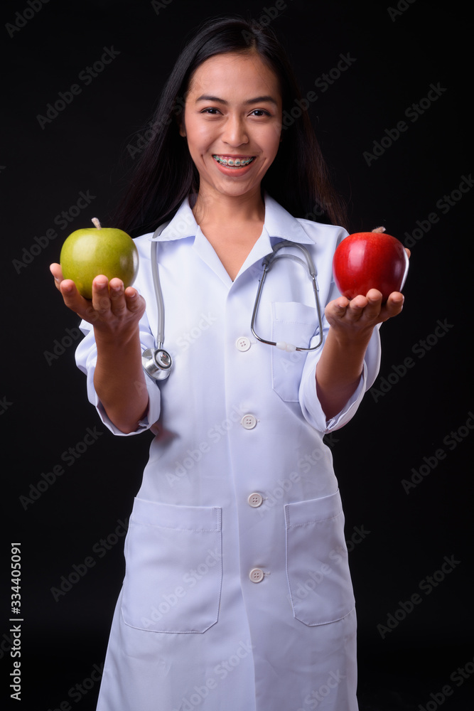 Happy young Asian woman doctor as nutritionist holding two apples Happy young Asian woman doctor as nutritionist holding two apples