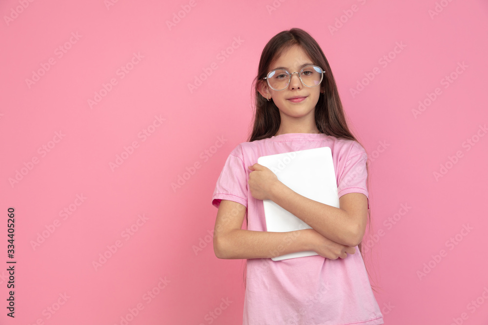 Holding tablet. Caucasian little girl portrait isolated on pink studio background. Cute brunette model in shirt. Concept of human emotions, facial expression, sales, ad, childhood. Copyspace. Holding tablet. Caucasian little girl portrait isolated on pink studio background. Cute brunette model in shirt. Concept of human emotions, facial expression, sales, ad, childhood. Copyspace.