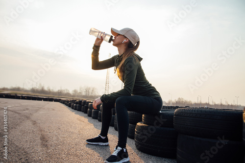 beautiful girl at morning workout drinks water from a bottle