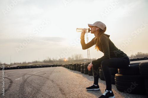 beautiful girl at morning workout drinks water from a bottle