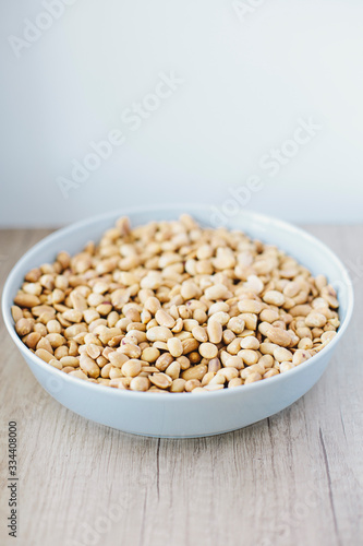 Peeled peanuts in blue plate on wooden background. Cooking peanut butter.