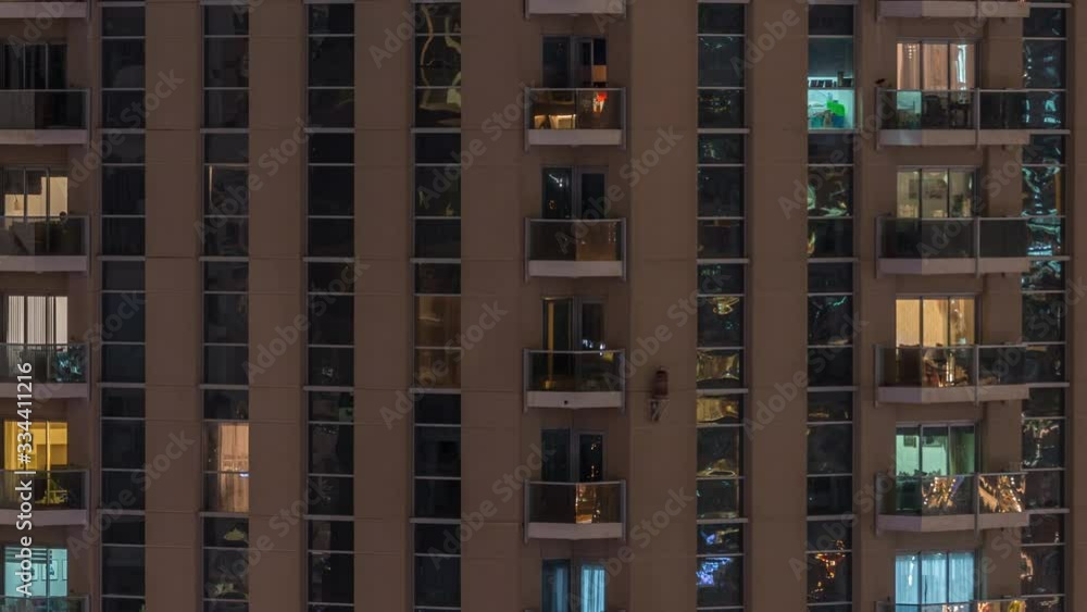 Rows of glowing windows with people in the interior of apartment building at night. Modern skyscraper in the city. Concept for business and modern life. Pan right Rows of glowing windows with people in the interior of apartment building at night. Modern skyscraper in the city. Concept for business and modern life. Pan right