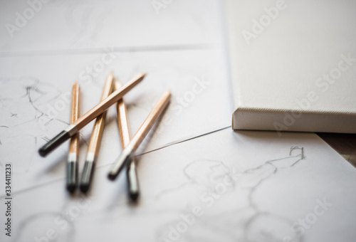 A top view flat lay of many figure drawing pencil and marker sketches. The artist worskspace with male and female drawings and pencils on the white paper  art  craft  creativity  inspiration  concepts