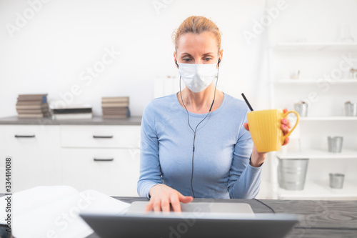 Online teacher with a protective mask tutoring over the internet. Trouble with drinking morning coffee.