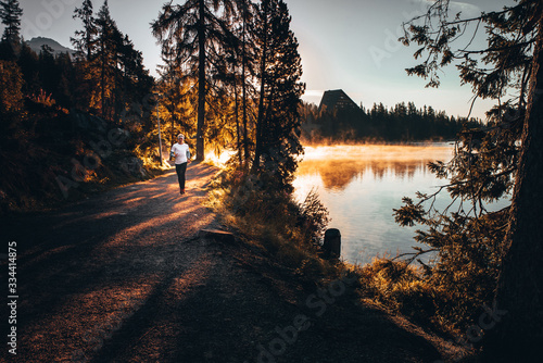 Trail runner in wild nature by lake, gold morning light in background photo
