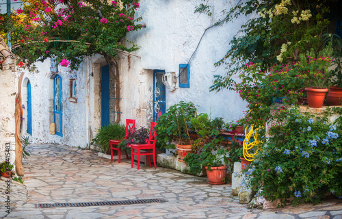 Gasse auf der Insel Korfu. Rote Stühle und blaue Türen.