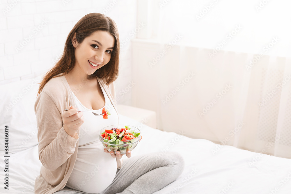 Pregnant woman enjoying fresh vegetable salad in bed Pregnant woman enjoying fresh vegetable salad in bed