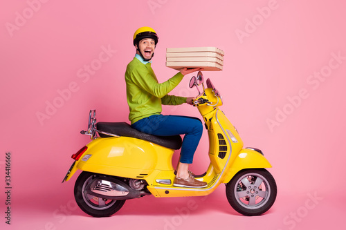 Profile side view portrait of his he nice attractive excited glad cheerful cheery guy driving moped bringing tasty yummy sweet dessert baked pie home order isolated over pink pastel color background © deagreez