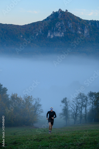 Active young man, runner train in misty autumn nature. Grey color tone