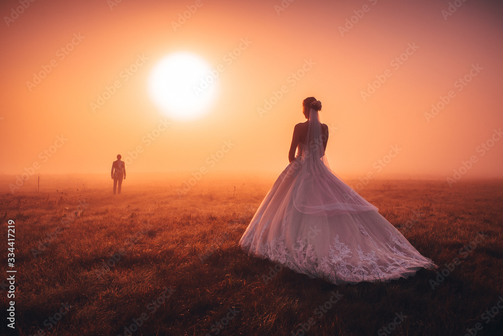Wedding couple in autumn morning. Brdie waiting groom in orange misty sunrise light. Romantic, mariage or valentine photo. Orange edit space Wedding couple in autumn morning. Brdie waiting groom in orange misty sunrise light. Romantic, mariage or valentine photo. Orange edit space