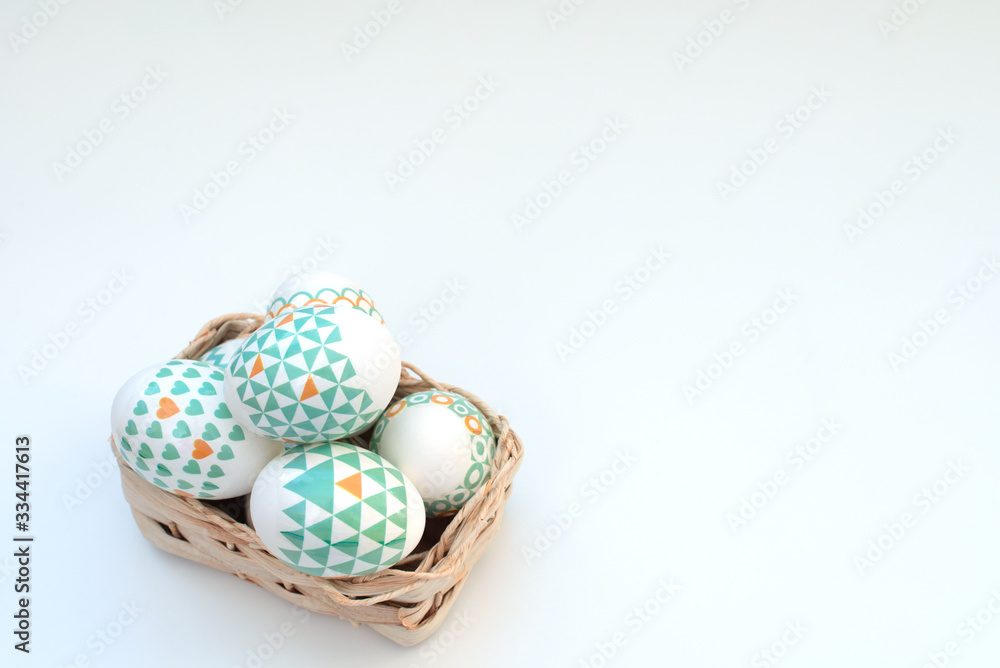 Decorated Easter eggs lie in the basket on white background. Happy Easter holiday concept. Greeting, invitation card. Flat lay style with copy space. Decorated Easter eggs lie in the basket on white background. Happy Easter holiday concept. Greeting, invitation card. Flat lay style with copy space.