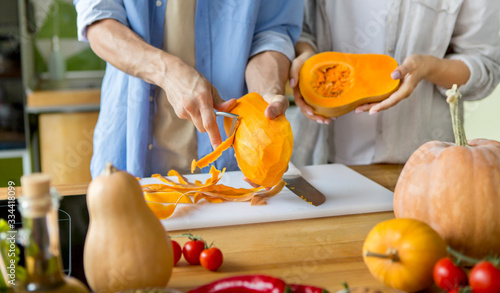 Unrecognizable vegan couple slicing and cleaning pumpkin