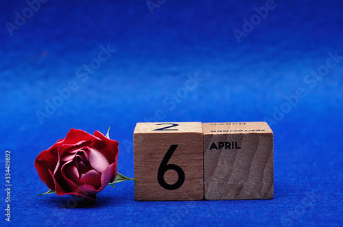 6 April on wooden blocks with a red rose on a blue background