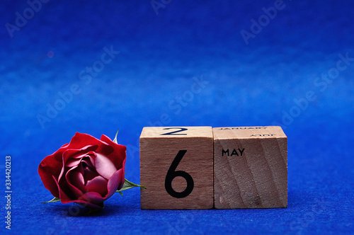 6 May on wooden blocks with a red rose on a blue background