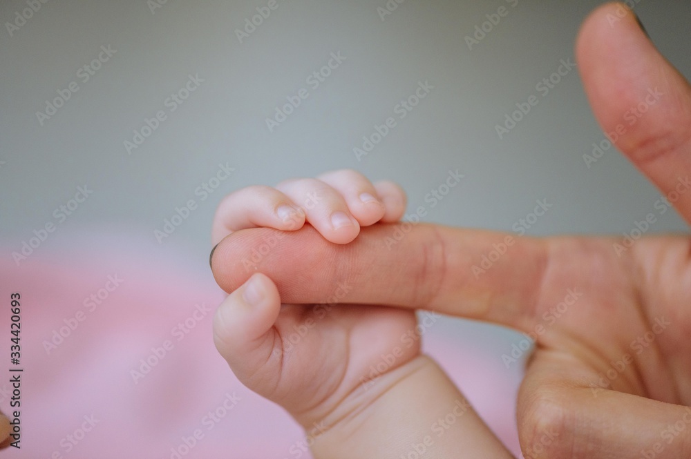 Baby hand holding mother finger. Closeup of baby hand into parents hands. Baby hand holding mother finger. Closeup of baby hand into parents hands.