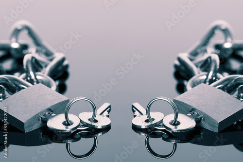 Padlock and chain with a set of keys reflected on a gloss surface. With colour toning