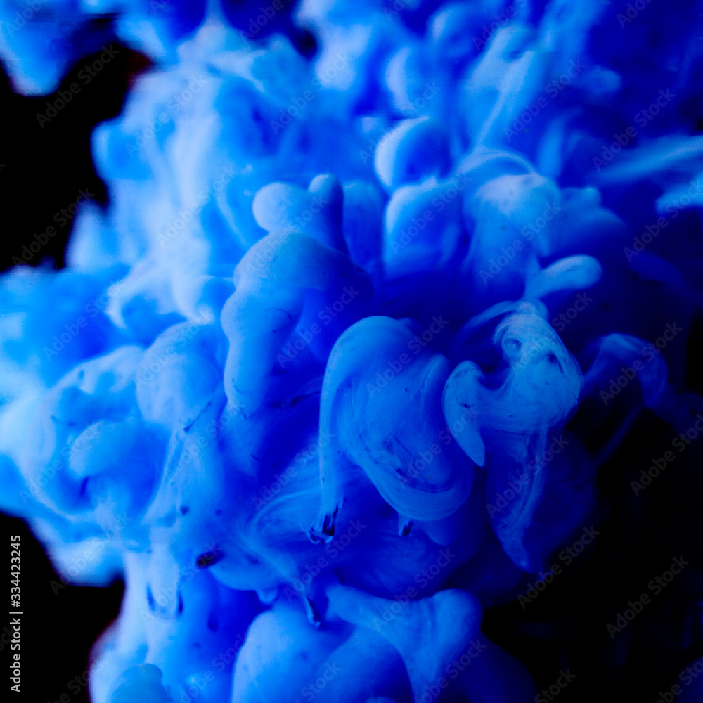 Abstract flowing liquid or blue ink in water on black background.