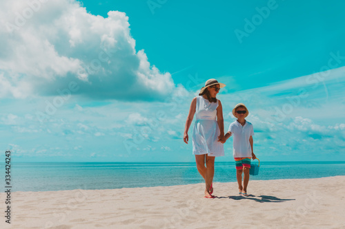 happy mother with son walk on beach, family at sea