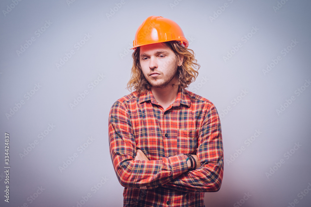 Handsome young man with protective helmet on his head and arms crossed Handsome young man with protective helmet on his head and arms crossed