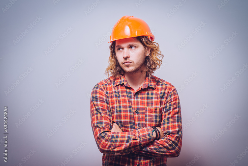 Handsome young man with protective helmet on his head and arms crossed Handsome young man with protective helmet on his head and arms crossed