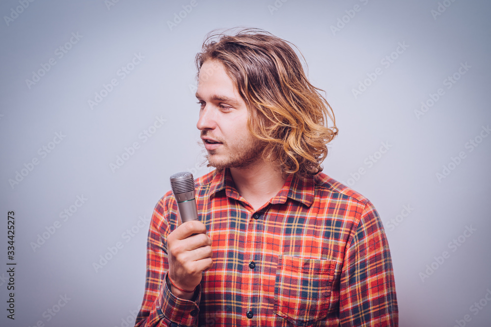 handsome man singing to the microphone. Emotional portrait of an attractive guy a gray background handsome man singing to the microphone. Emotional portrait of an attractive guy a gray background
