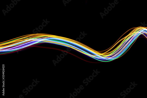Multi color light painting photography, gold, red, green and blue waves of vibrant color against a black background © LizFoster