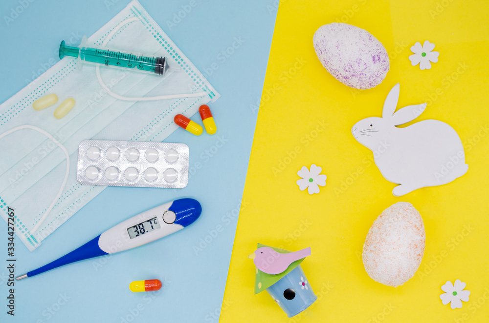 Сolorful eggs, decorations, flowers and an Easter Bunny on a yellow background. Medical mask, pills, syringe, thermometer on a blue background. Holiday concept during the Covid-19 epidemic, quarantine Сolorful eggs, decorations, flowers and an Easter Bunny on a yellow background. Medical mask, pills, syringe, thermometer on a blue background. Holiday concept during the Covid-19 epidemic, quarantine
