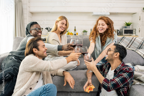 Joyful young multicultural friends clinking with glasses of red wine