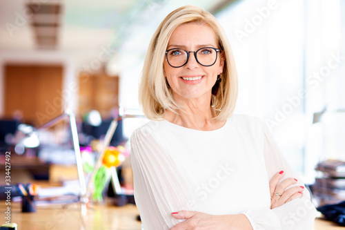 Portrait shot of attractive senior businesswoman standing in the office with arms crossed