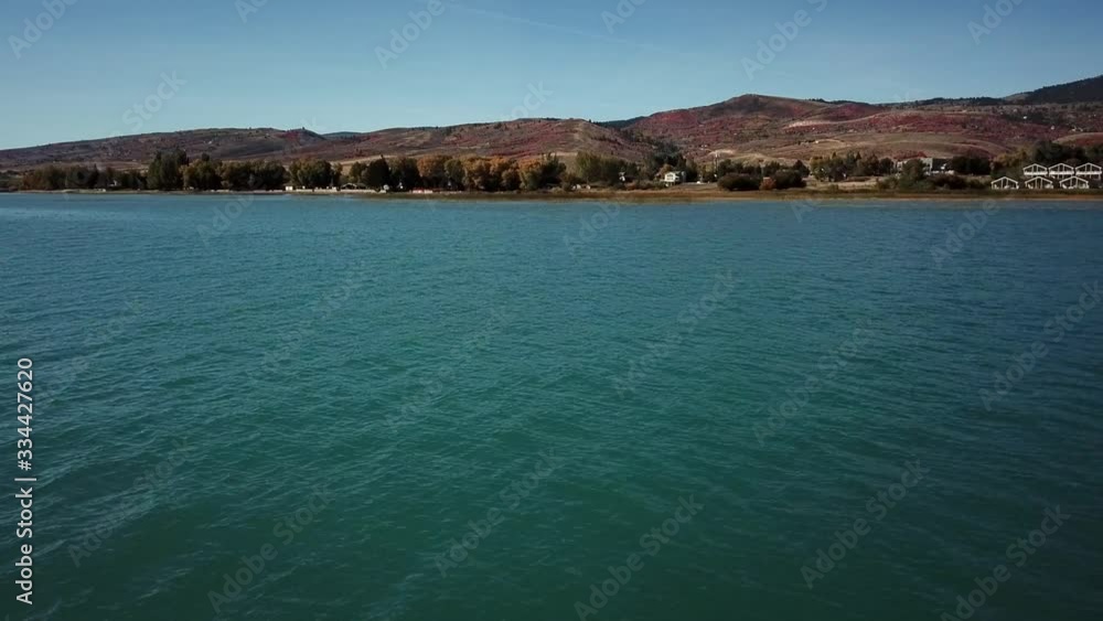 Drone shot flying over Bear Lake, Utah. Pine trees and mountains are seen in view. Drone shot flying over Bear Lake, Utah. Pine trees and mountains are seen in view.