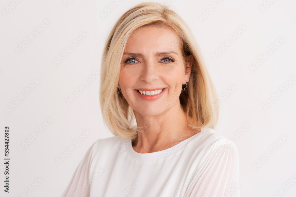 Headshot of blond senior woman while standing at isolated white background Headshot of blond senior woman while standing at isolated white background