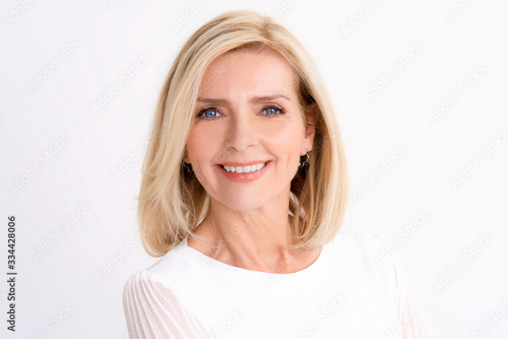 Headshot of blond senior woman while standing at isolated white background Headshot of blond senior woman while standing at isolated white background