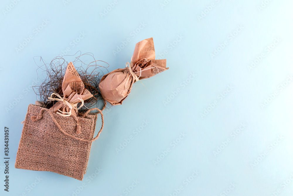 Naklejka premium Easter flat layout of burlap, eggs in craft paper on a blue background. The concept of eco-friendly minimalistic consumption of gifts. Copy space