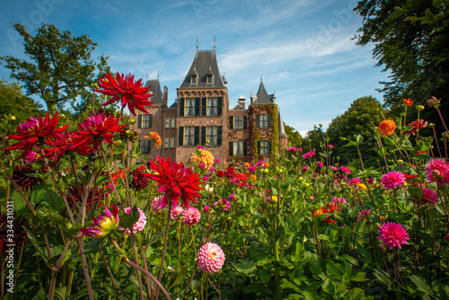 Fototapeta Naklejka Na Ścianę i Meble -  Garden with flowering dahlias in shades of orange and red in front of Keukenhof castle on a sunny day 