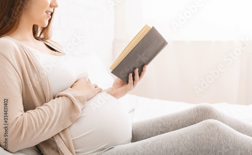 Smiling pregnancy reading ibook sitting on bed photo