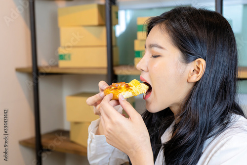 Cute Asian woman eating delicious pizza