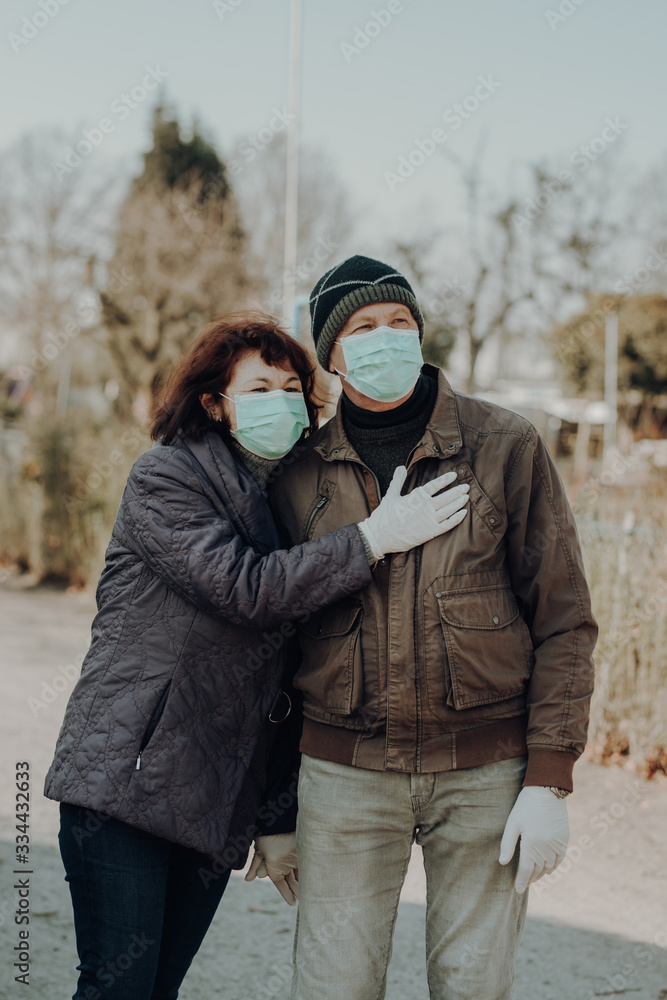 couple of two seniors wearing facial masks and gloves walking outside couple of two seniors wearing facial masks and gloves walking outside