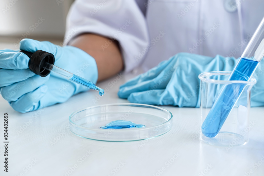 Fototapeta premium Biochemistry laboratory research, Scientist or medical in lab coat holding test tube with using reagent with drop of color liquid over glass equipment working at the laboratory
