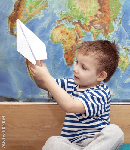 The boy plays with paper planes. On a world map background