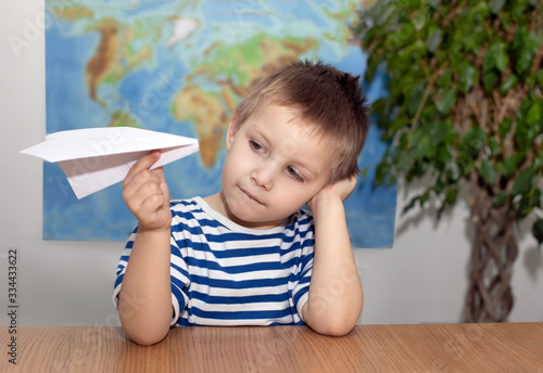 Boy playing with paper plane. On a world map background