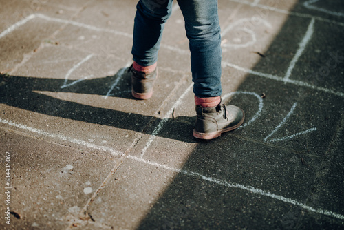 adorable toddler girl playing hopscotch game outdoor, cold season